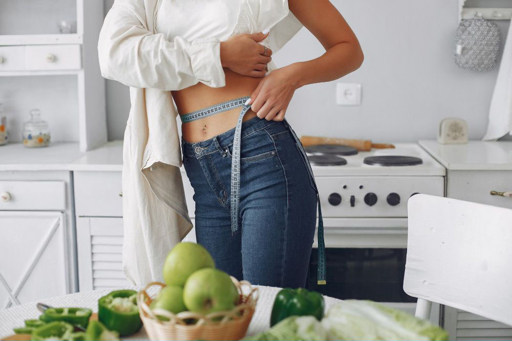 Beautiful sporty woman kitchen with vegetables