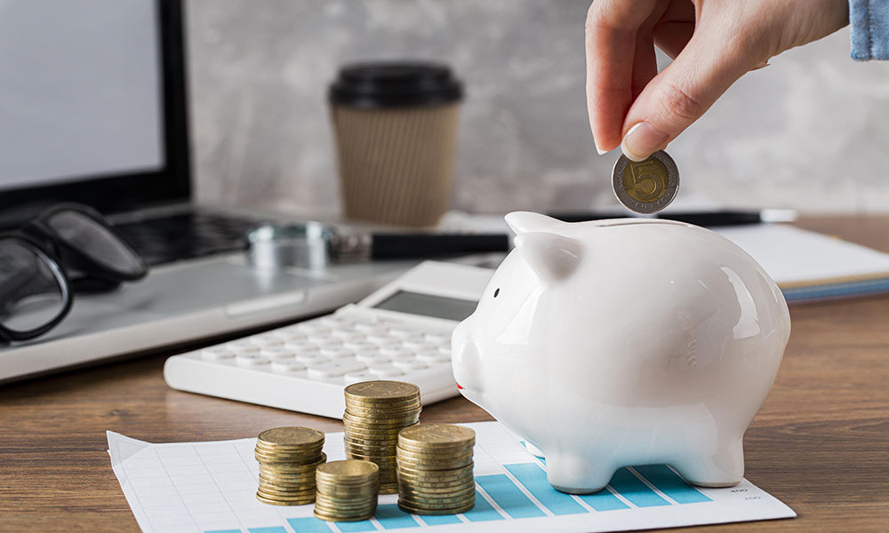 Close up of a female hand throwing a coin into a piggy bank