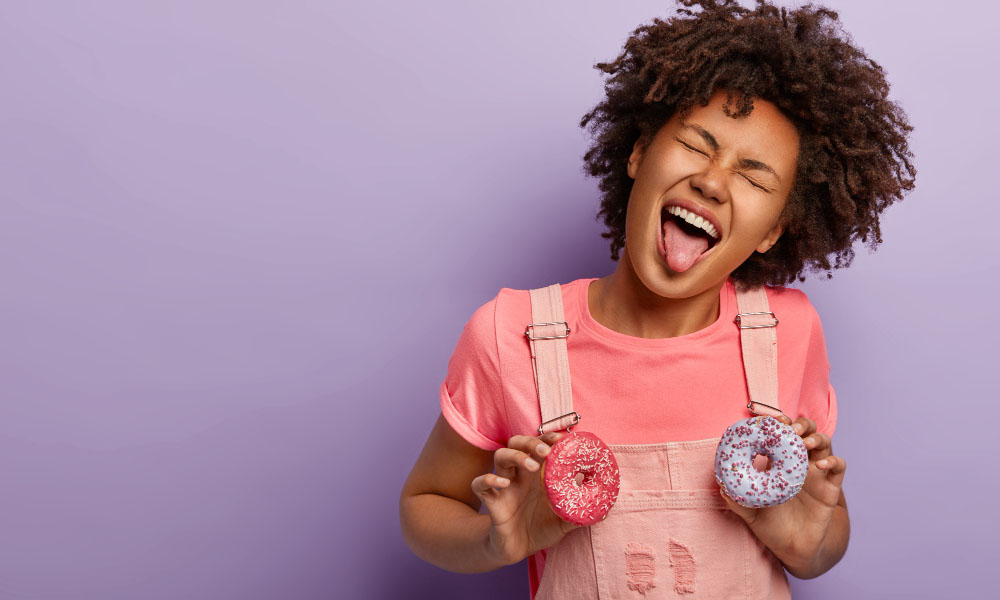 Funny girl with curly hair sticks tongue holds two delicious packages