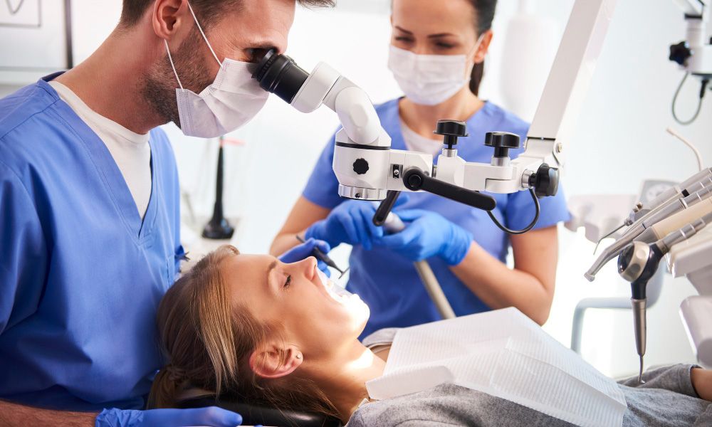 Male dentist working with dental microscope