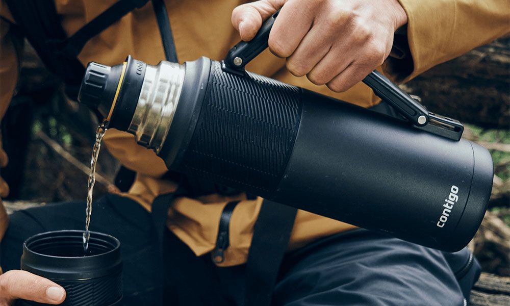Man pours tea from thermos into a mug