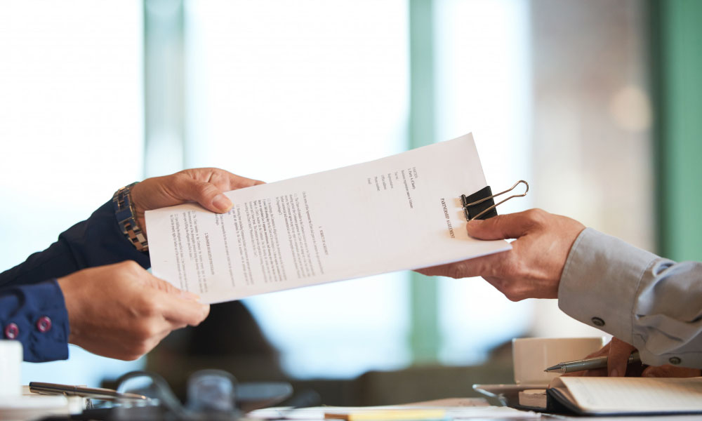 Two people pass documents to each other