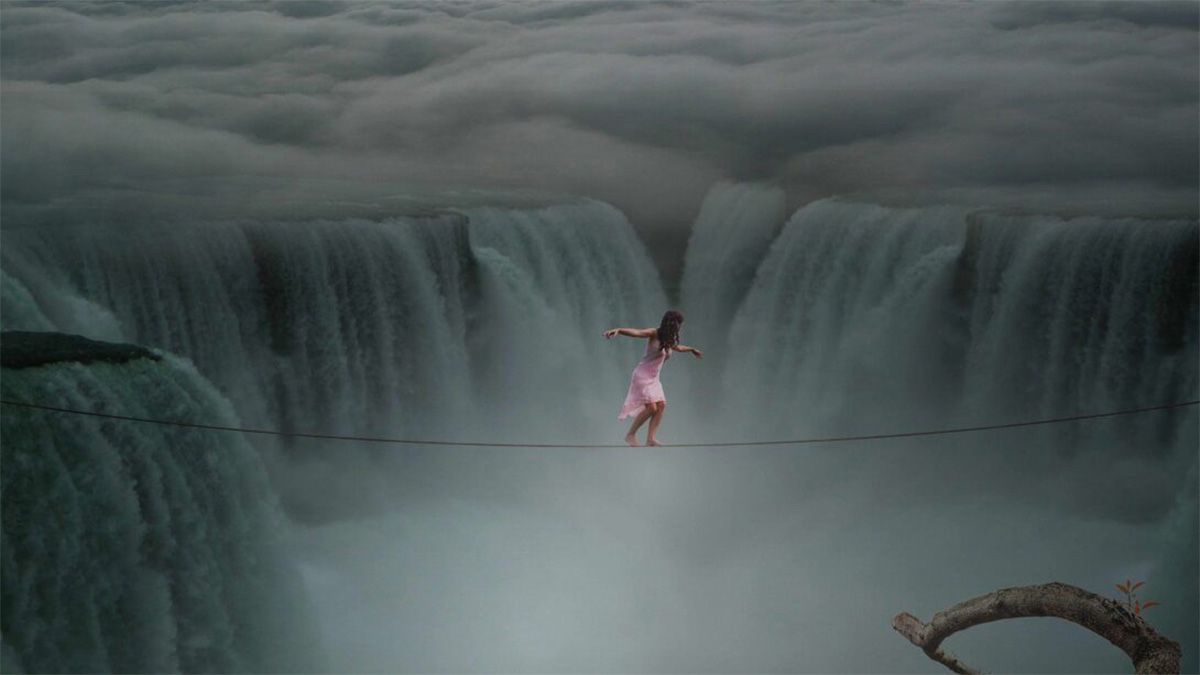 Woman walks on a rope between waterfalls